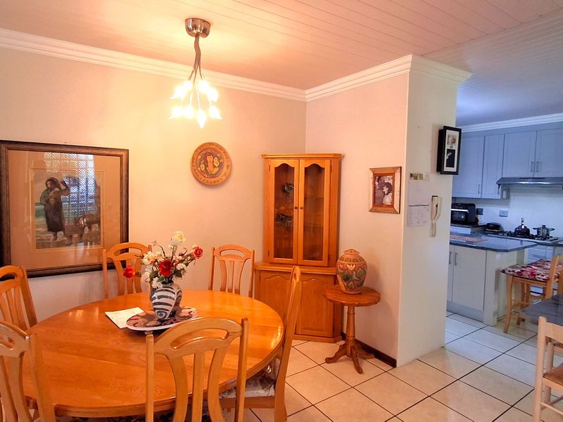 Open plan dining area adjacent to a functional kitchen with tiled flooring, crown molding, and classic cabinetry.