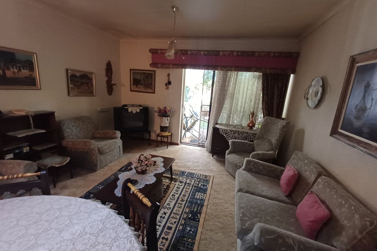 A living room featuring carpeted flooring and a sliding glass door providing access to an outdoor patio area.