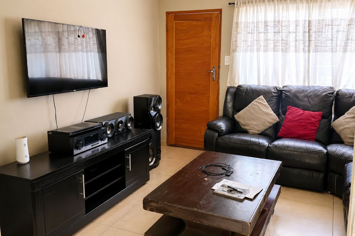 A functional living room featuring tiled flooring and a solid wooden door, providing a comfortable and practical space for relaxation.