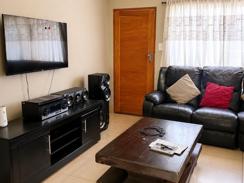 A functional living room featuring tiled flooring and a solid wooden door, providing a comfortable and practical space for relaxation.