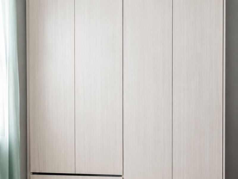A bedroom featuring a modern, light-wood finish built-in wardrobe with integrated drawers and neutral tiled flooring.