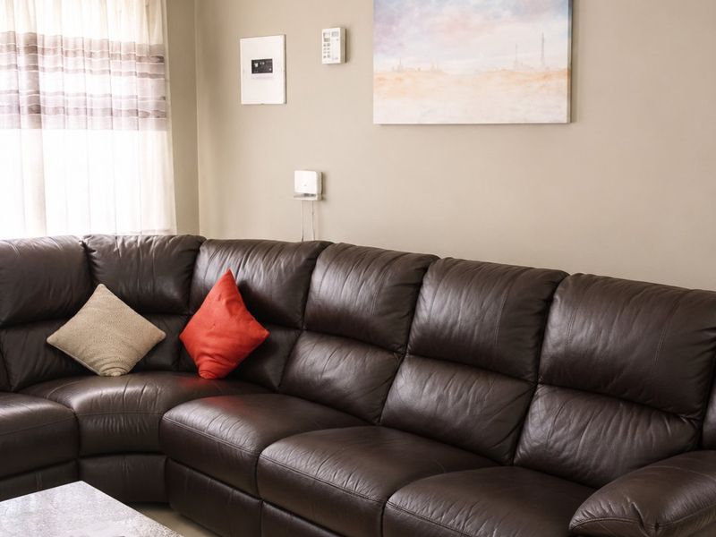 A comfortable living room featuring tiled flooring, recessed ceiling lighting, and decorative cornice detailing.