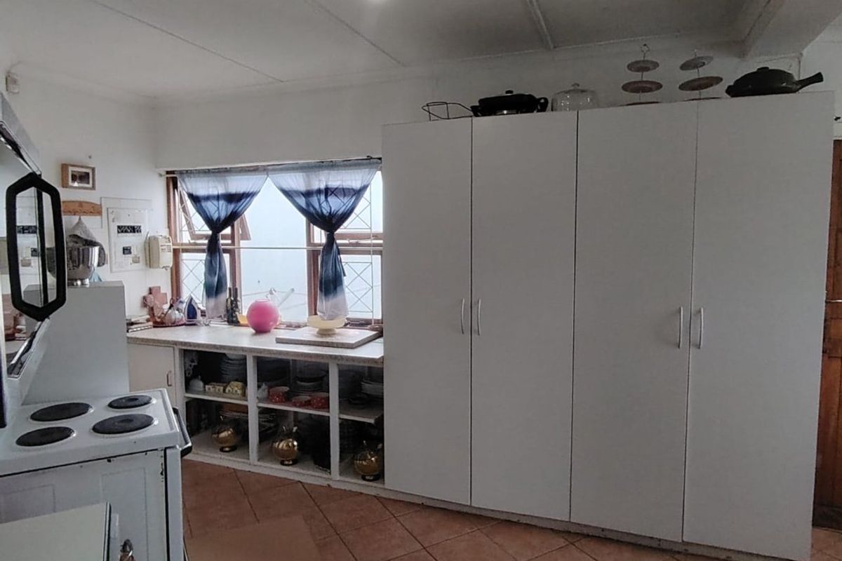 A functional kitchen featuring built-in white cabinetry, tiled flooring, and an electric stove, offering potential for modern updates.