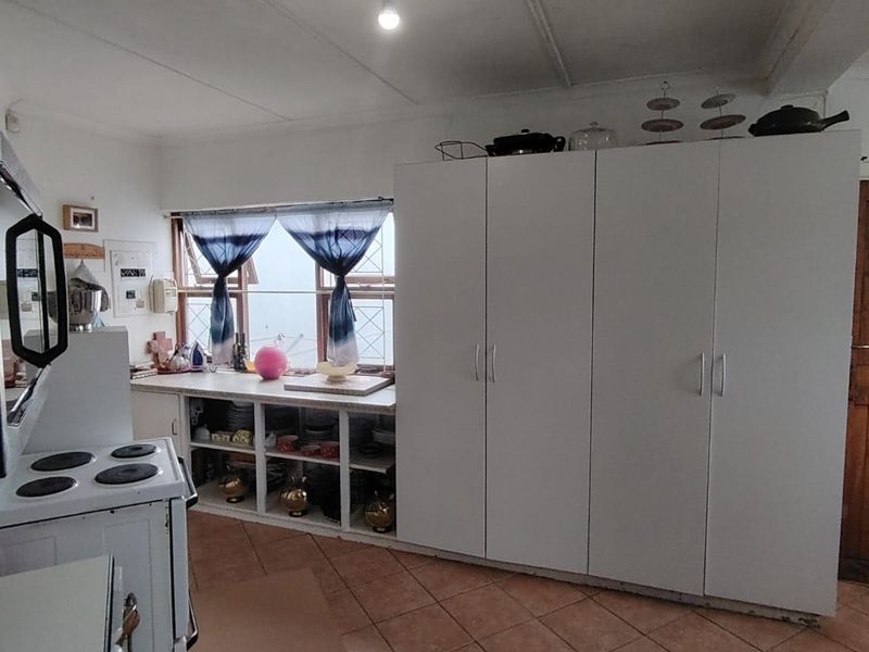 A functional kitchen featuring built-in white cabinetry, tiled flooring, and an electric stove, offering potential for modern updates.