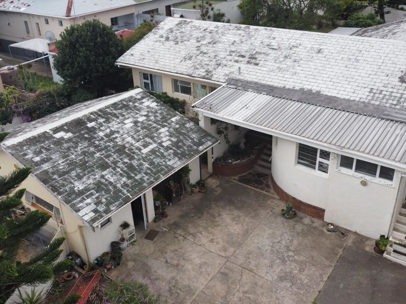 Aerial view of the property showing the main house and detached garage with significant roof maintenance required.