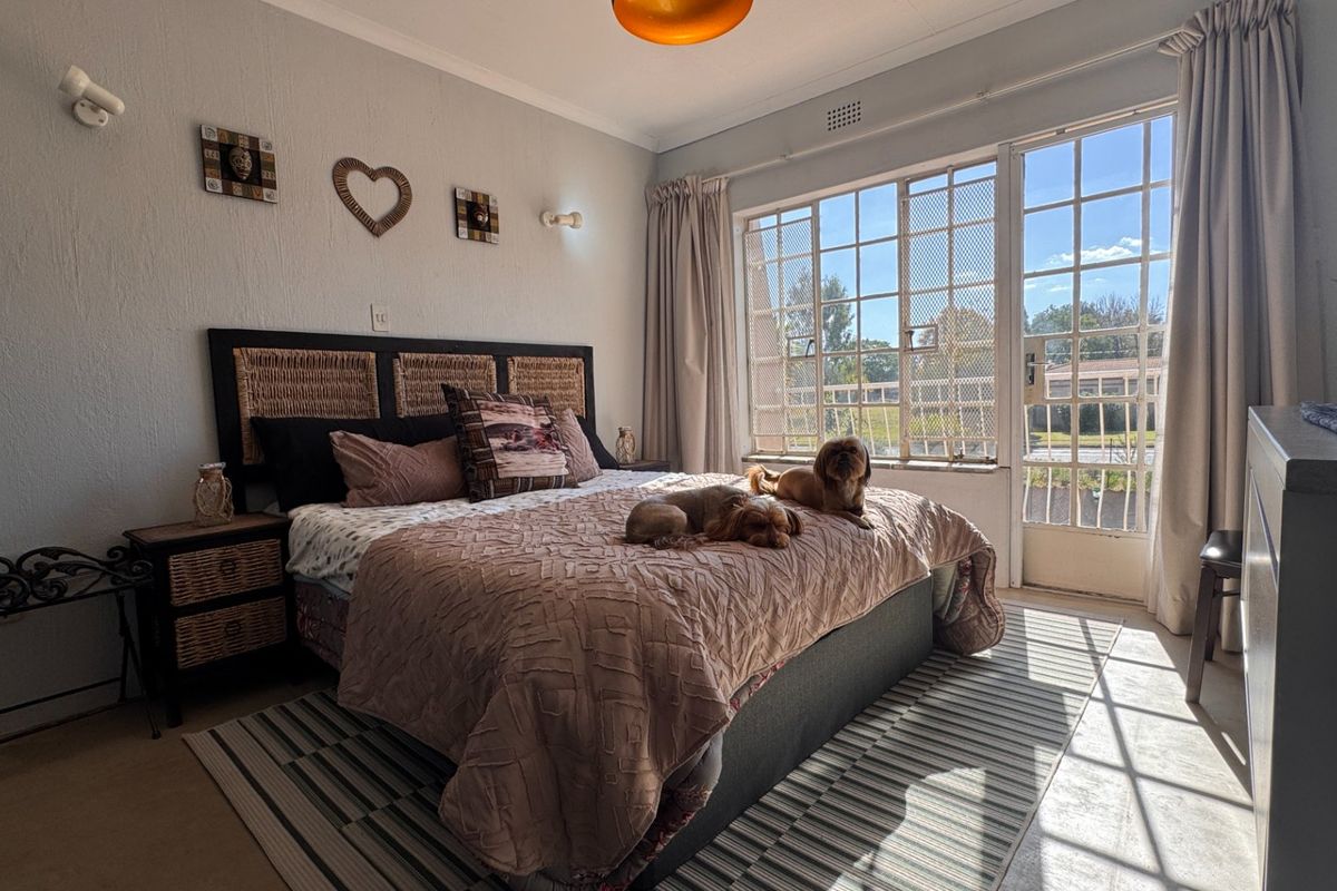 A bedroom featuring large windows with security bars and direct access to an outdoor area, providing natural light and ventilation.