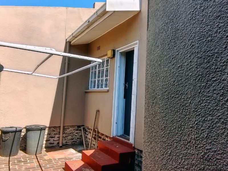 Rear exterior area of the townhouse featuring brick paving, a wall-mounted washing line, and concrete steps leading to a secure entrance.