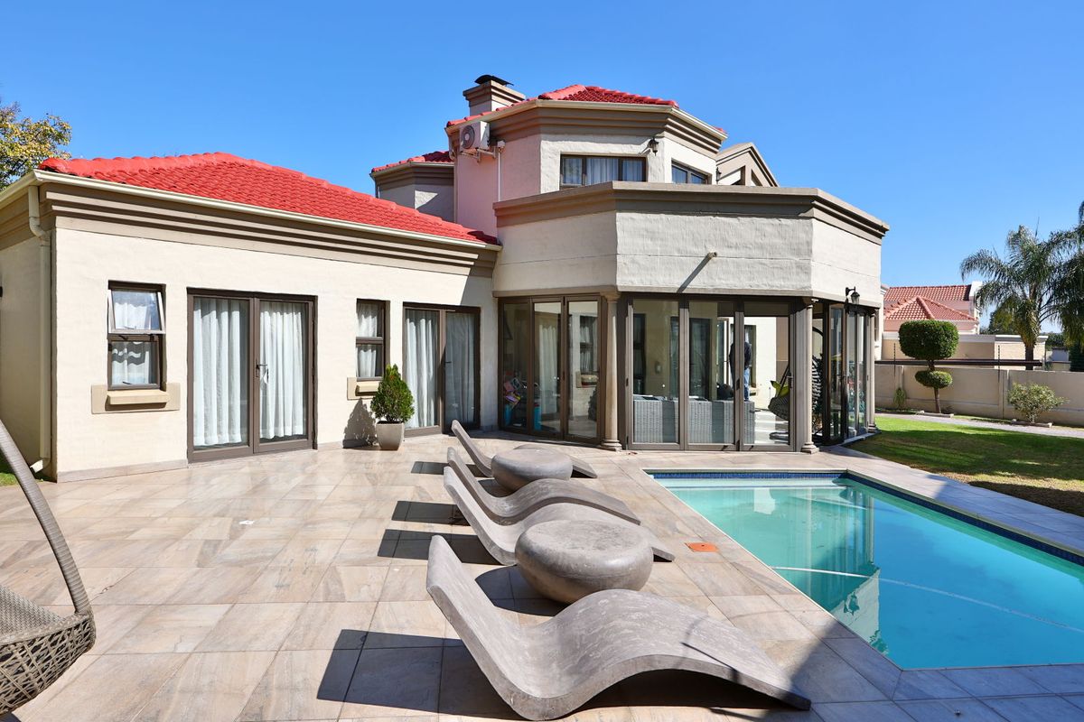 Rear view of the property featuring a tiled patio area, swimming pool, and multi-level architectural design with large glass sliding doors.