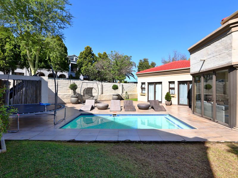 Outdoor pool area featuring a tiled deck, swimming pool, and direct access to the main house through large sliding glass doors.