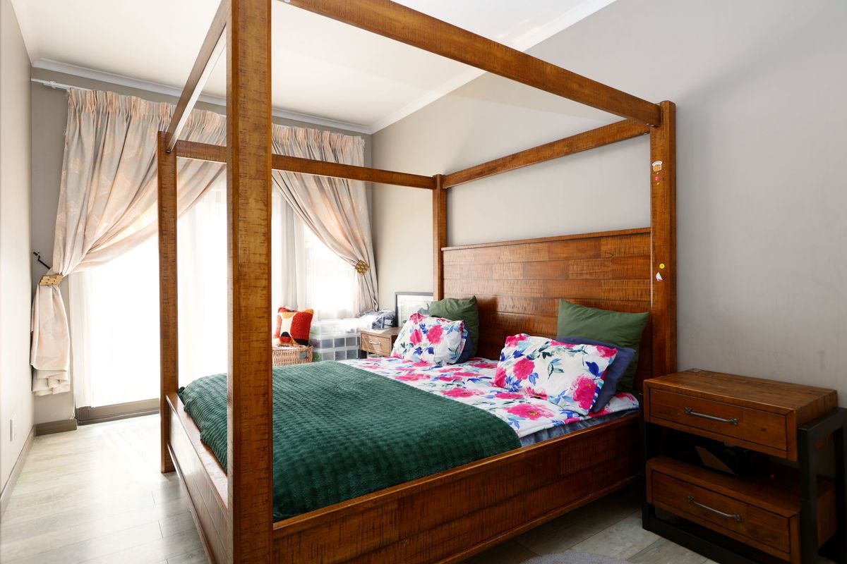 A well-lit bedroom featuring laminate flooring and a sliding glass door providing access to natural light.