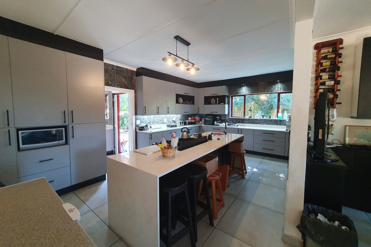 Modern kitchen featuring a central island with quartz countertops, extensive built-in cabinetry, and tile flooring, offering a functional and contemporary cooking space.