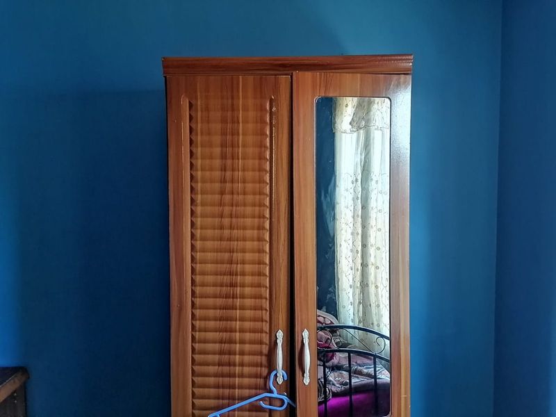 A bedroom interior featuring blue painted walls and a wooden wardrobe.