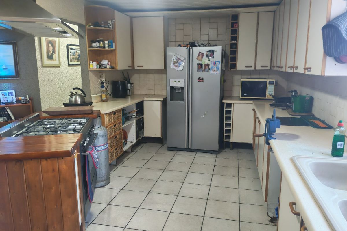 A functional kitchen featuring built-in cabinetry, a gas stove with extractor fan, and tiled flooring, offering potential for modernization and aesthetic updates.