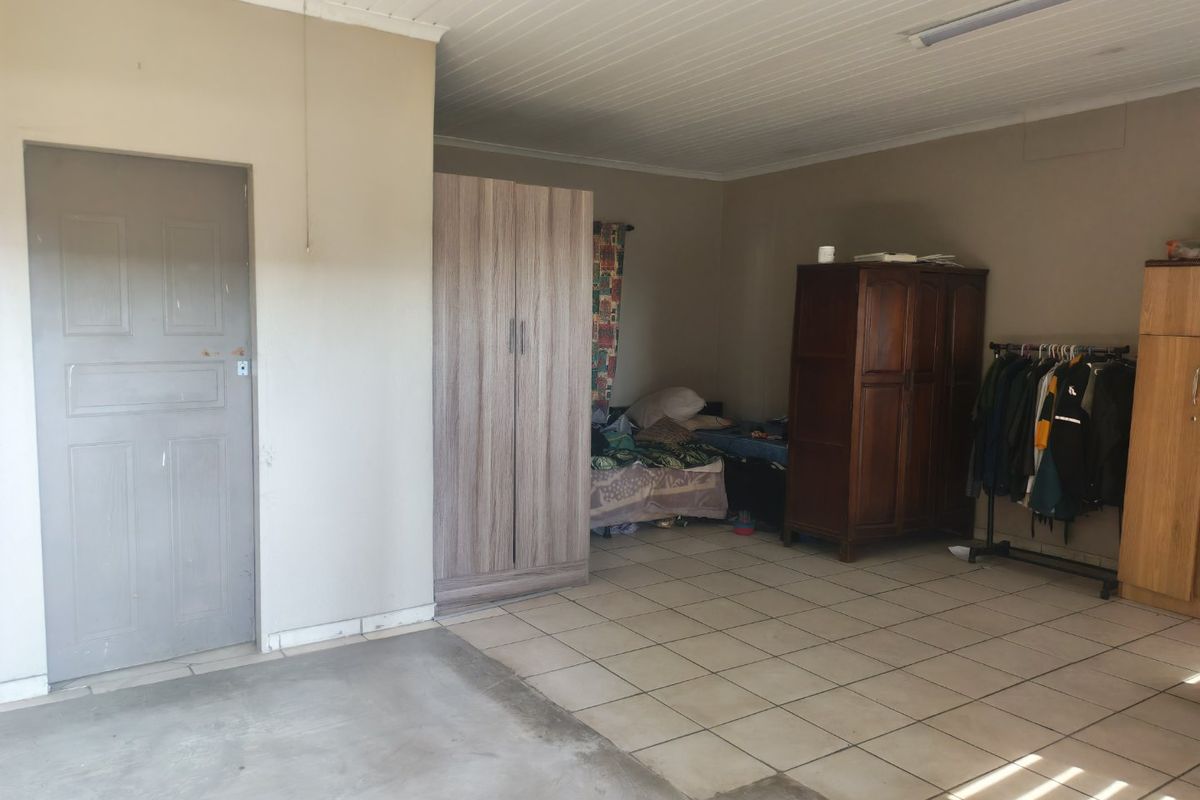 A bedroom featuring tiled flooring and a tongue and groove ceiling, currently used as a multi-purpose living and storage space.
