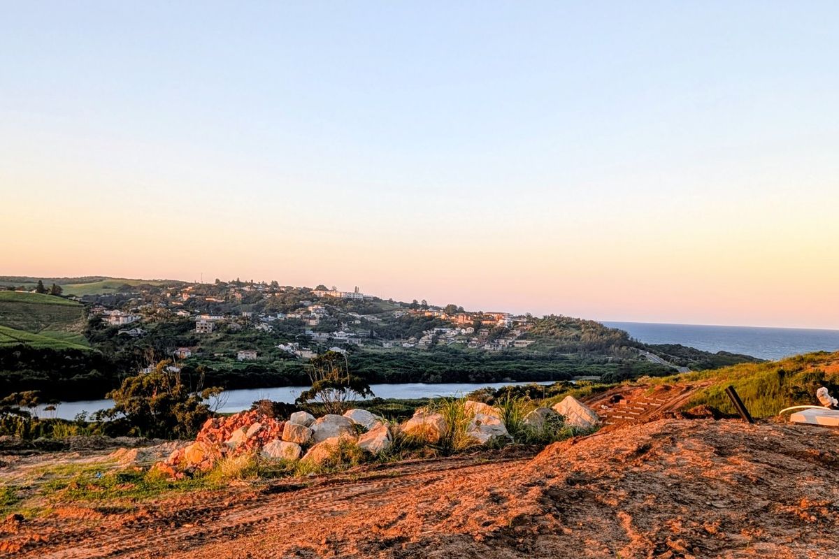 A scenic elevated view overlooking a coastal landscape, water body, and surrounding residential area at sunset.