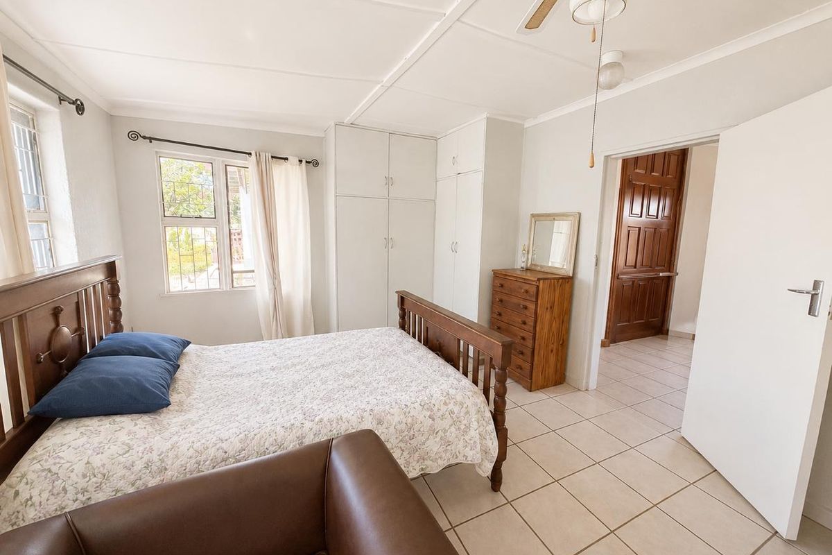 A bedroom featuring built-in cupboards, tiled flooring, and a ceiling fan, providing a functional and well-lit living space.