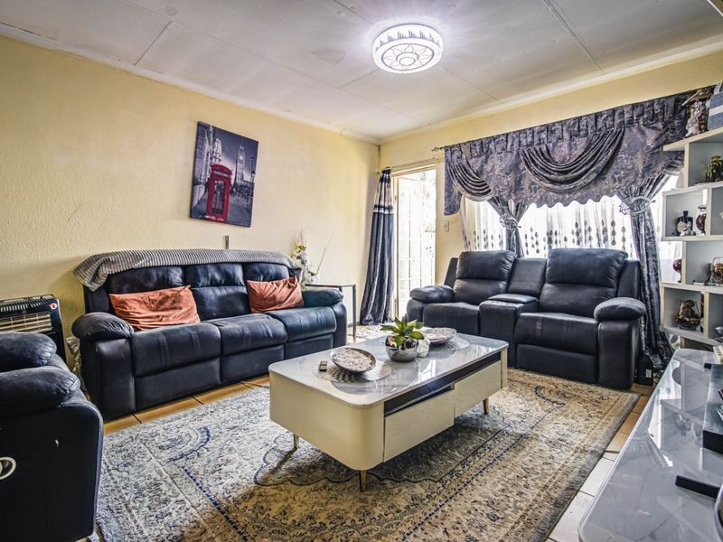 A living room featuring tiled flooring and a sliding glass door, showing signs of wear on the ceiling finishes.