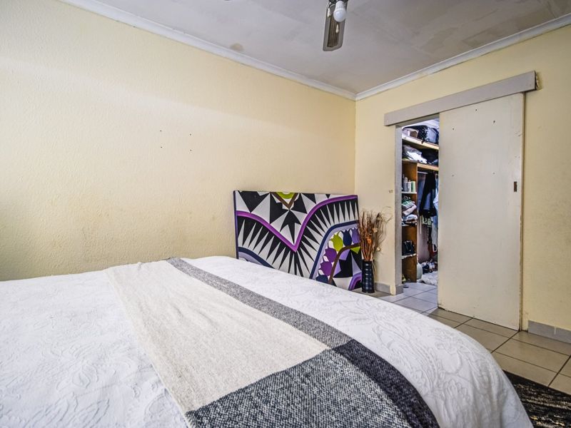 Bedroom featuring tiled flooring, a built-in closet with a sliding door, and a ceiling fan. The ceiling requires maintenance and repair.