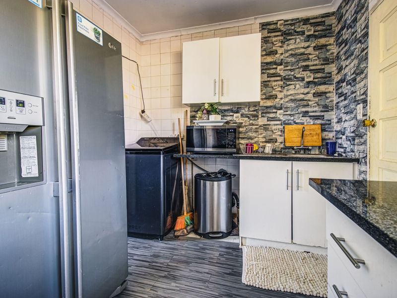 Compact kitchen featuring granite countertops, tiled backsplash, and built-in cabinetry, offering a functional layout with potential for cosmetic updates.