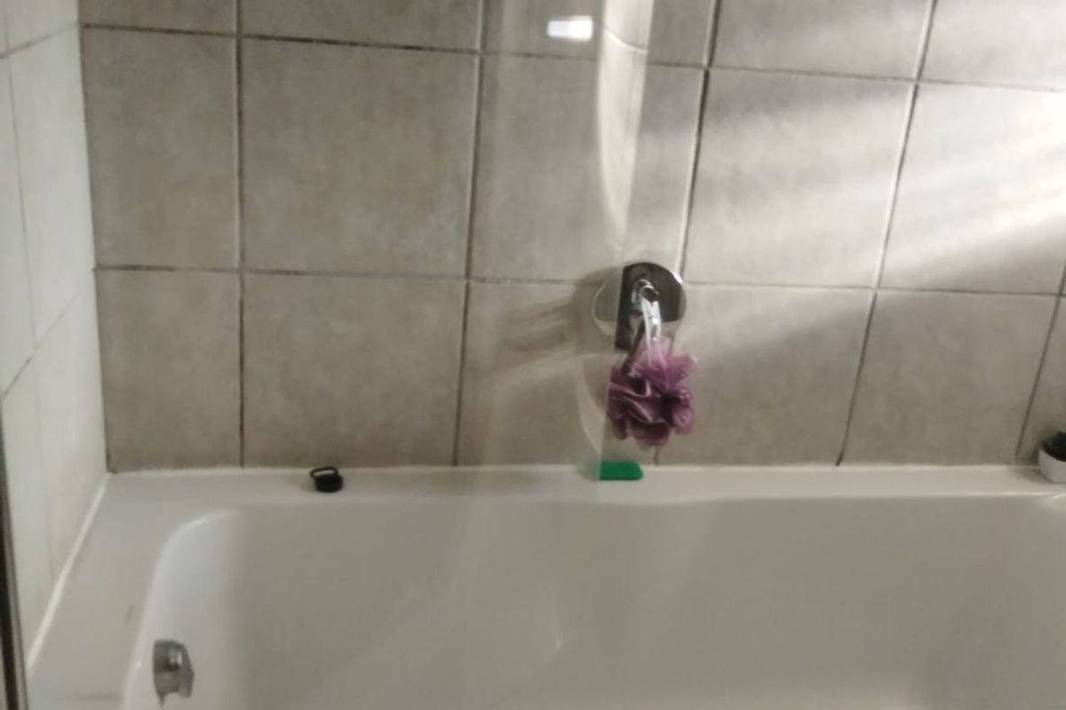 A functional bathroom featuring a built-in bathtub with a glass screen and tiled wall surround.