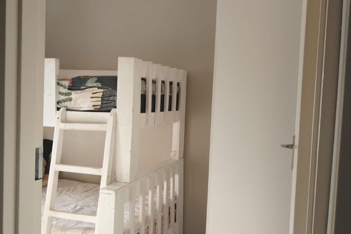A compact bedroom featuring tiled flooring and a neutral wall finish, viewed through a doorway.
