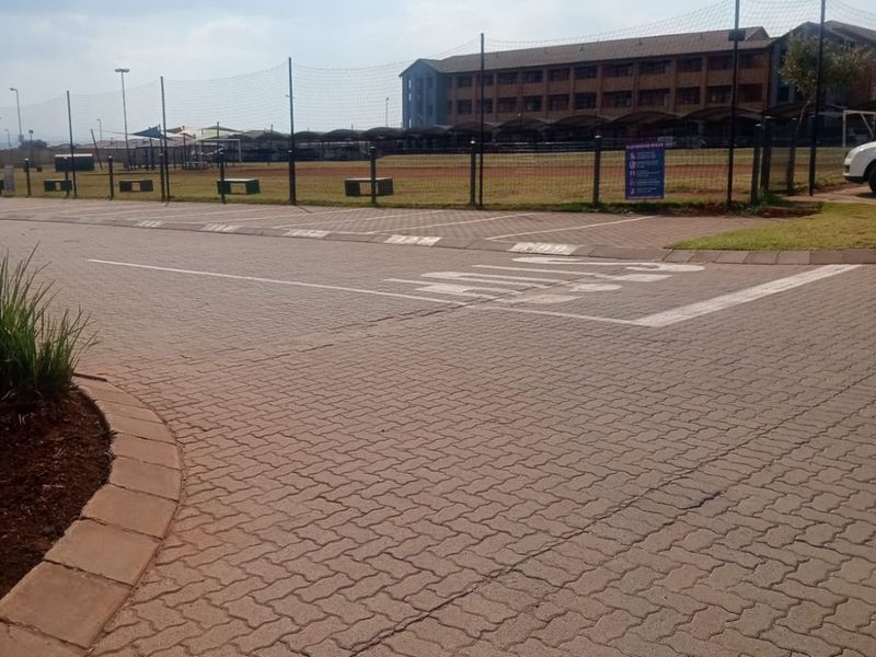 A view of the paved driveway and parking area leading towards the apartment complex grounds and recreational facilities.