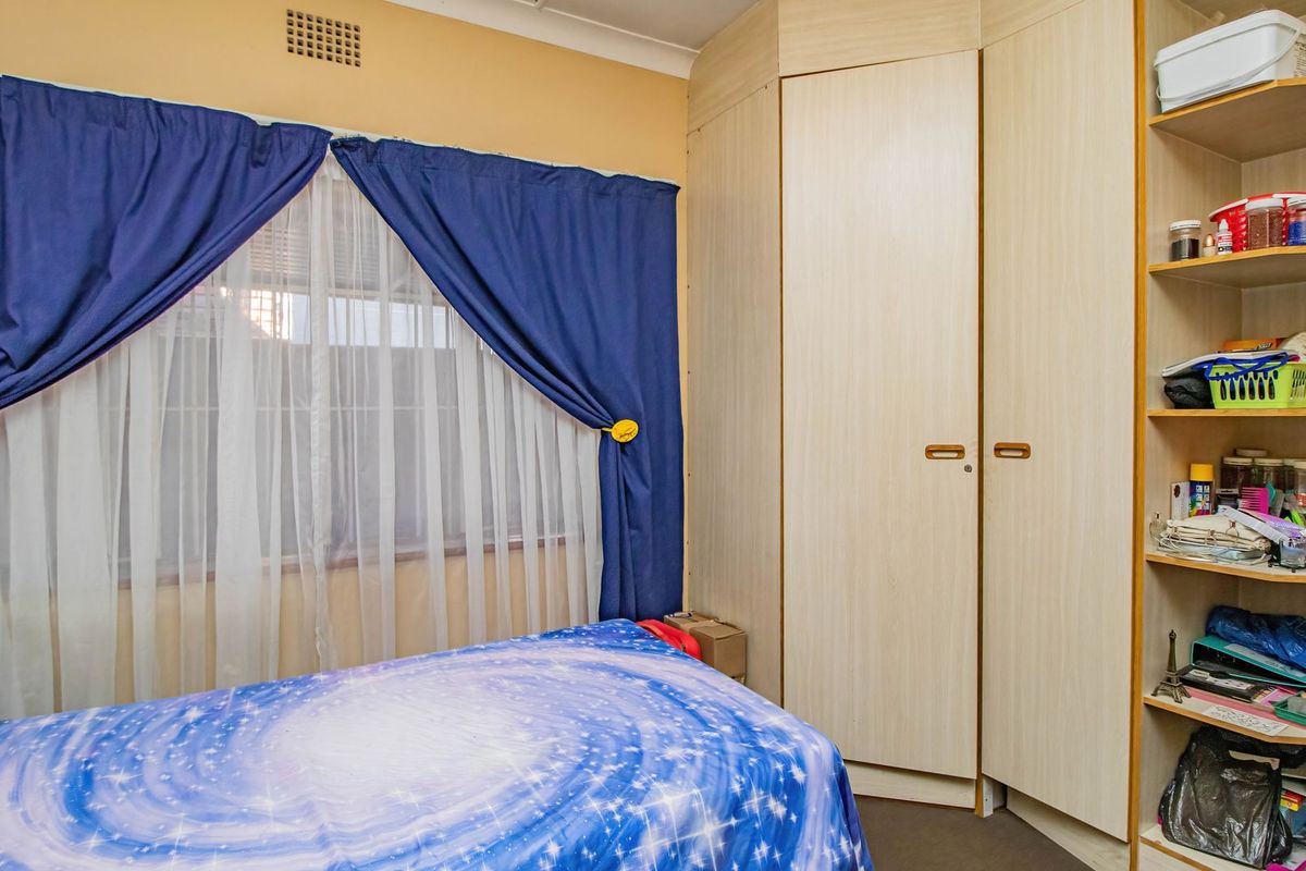 A bedroom featuring built-in light wood-grain cupboards and integrated open shelving units.