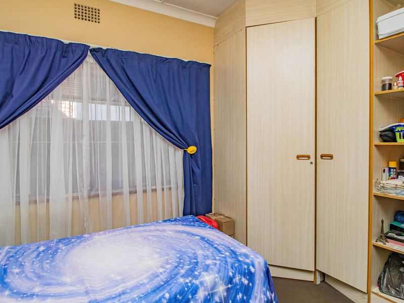 A bedroom featuring built-in light wood-grain cupboards and integrated open shelving units.