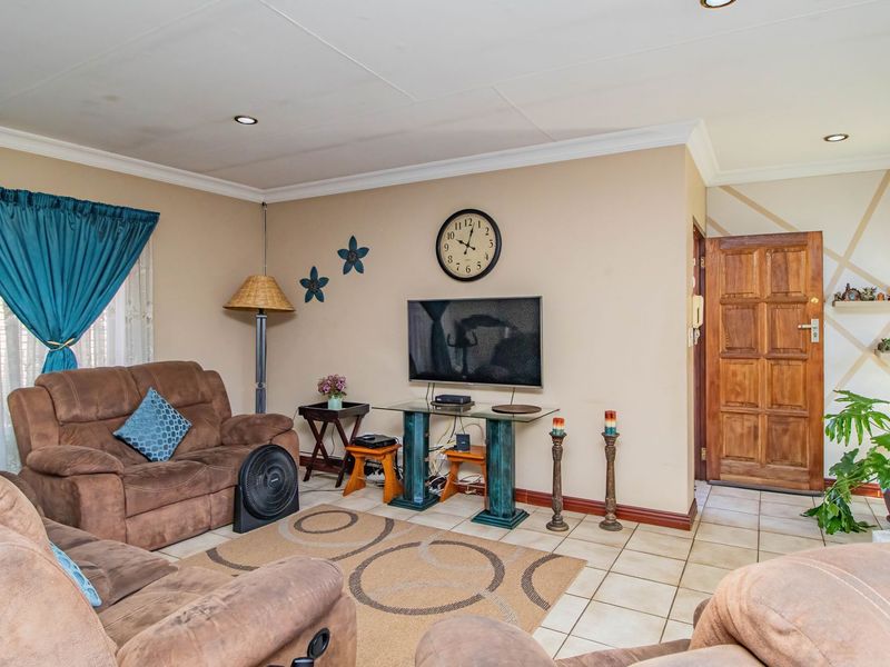 A comfortable living room featuring tiled flooring, recessed downlighting, and a solid timber entrance door, providing a functional and welcoming space.