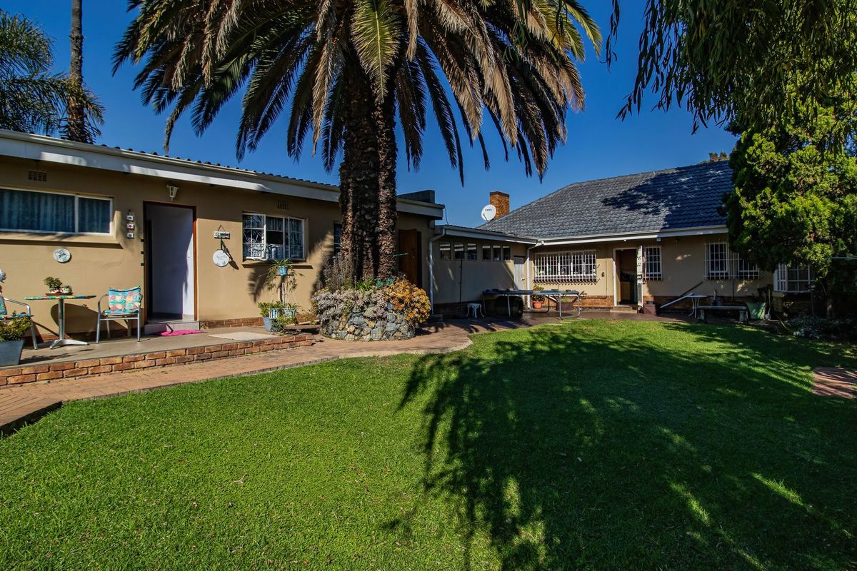 A spacious rear garden featuring a well-maintained lawn, brick paved patio areas, and established landscaping, providing a private outdoor living space.