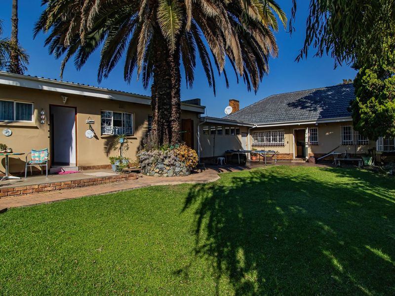 A spacious rear garden featuring a well-maintained lawn, brick paved patio areas, and established landscaping, providing a private outdoor living space.