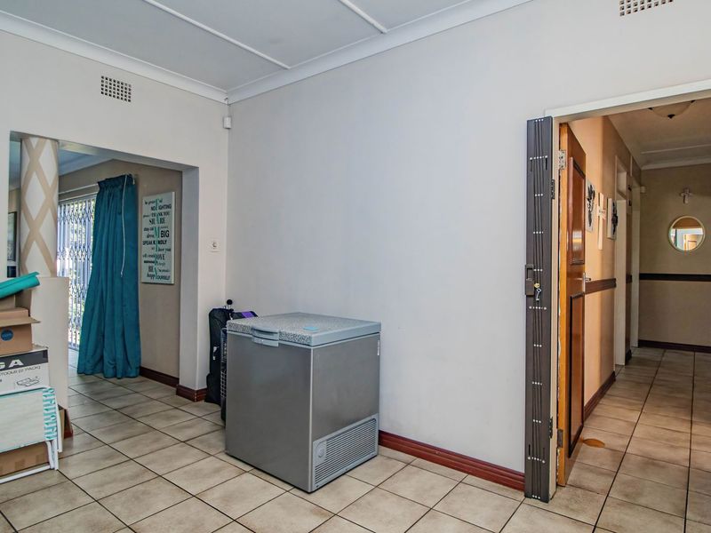 A neutral hallway space featuring tiled flooring, a coved ceiling, and a security gate leading to an adjacent room.