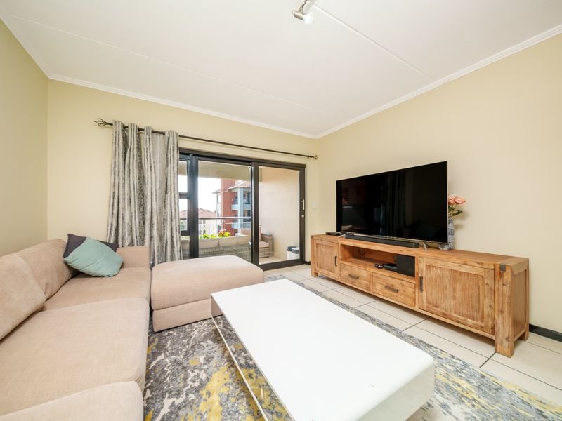 A comfortable living room featuring tiled flooring and a sliding glass door providing access to an outdoor balcony area.