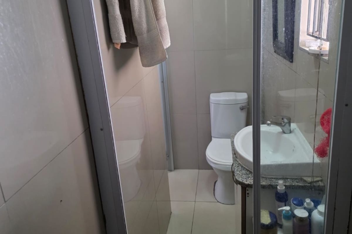 A compact bathroom featuring a toilet, vanity with basin, and a shower enclosure with tiled finishes.