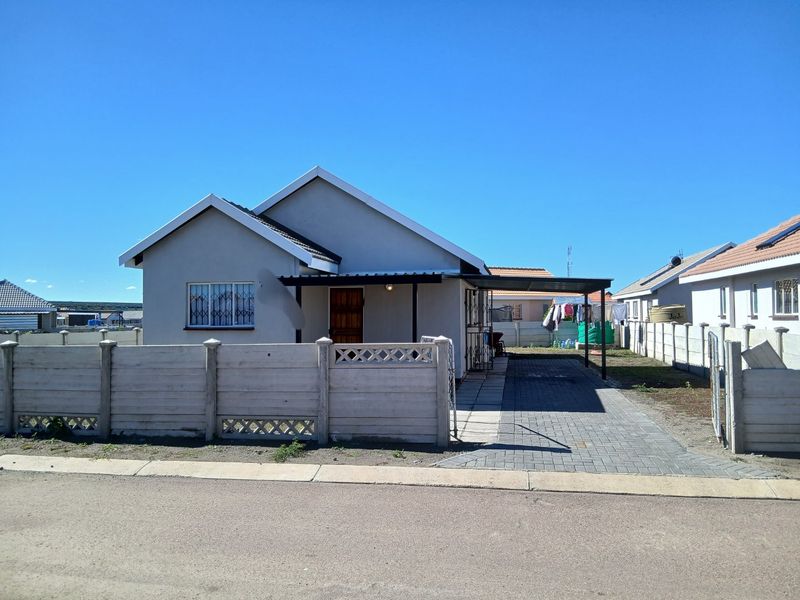 Front view of a detached house featuring a paved driveway, carport, and secure precast concrete boundary walling.
