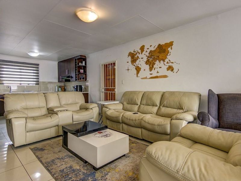 Open-plan living area featuring tiled flooring, integrated kitchen cabinetry, and a security gate, providing a functional and connected layout.