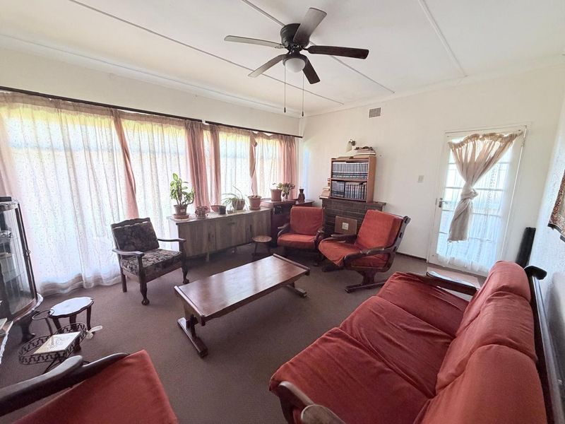 A spacious living room featuring a brick fireplace, ceiling fan, and large glass sliding doors that provide ample natural light.