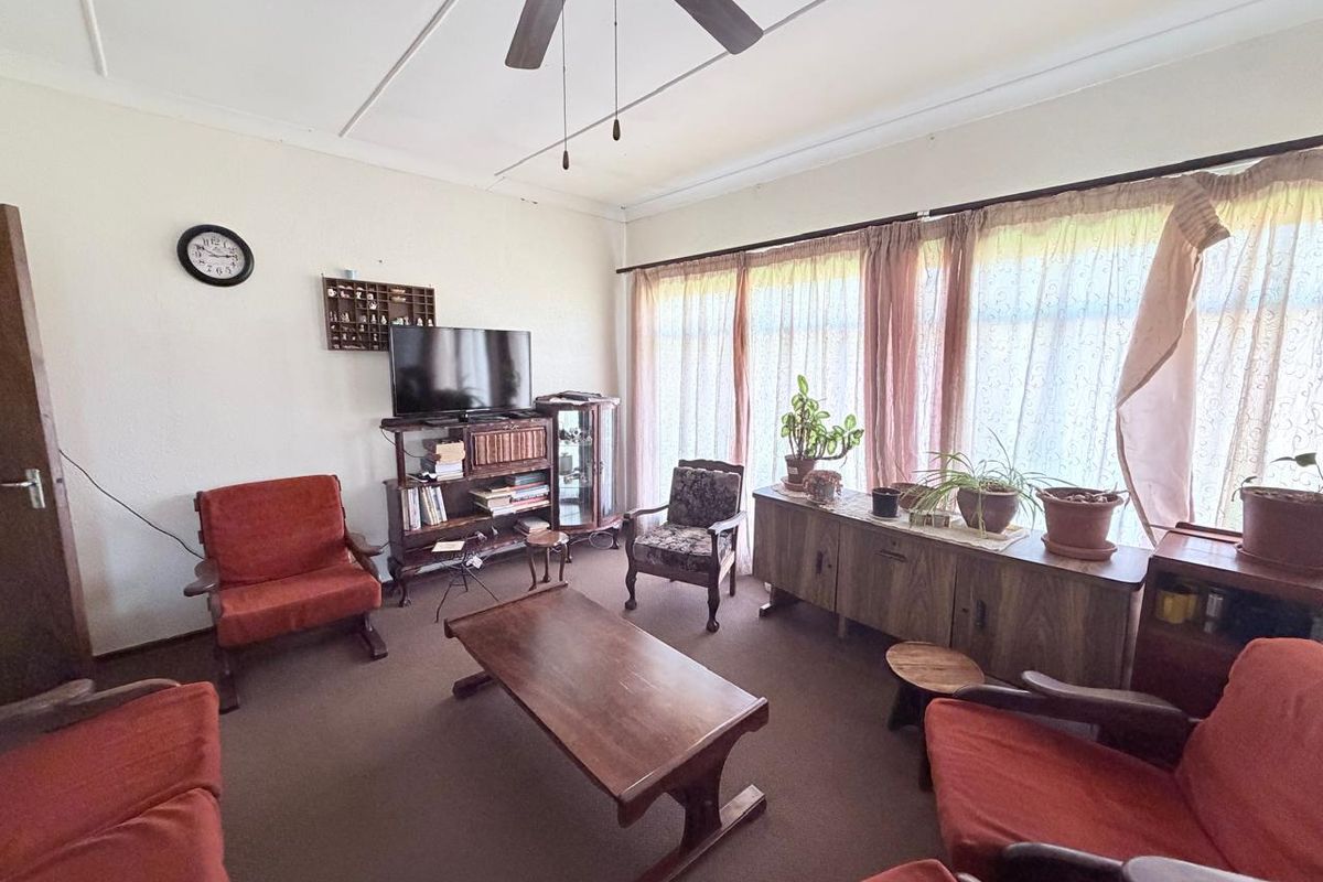 A living room featuring a ceiling fan and large windows that provide natural light.