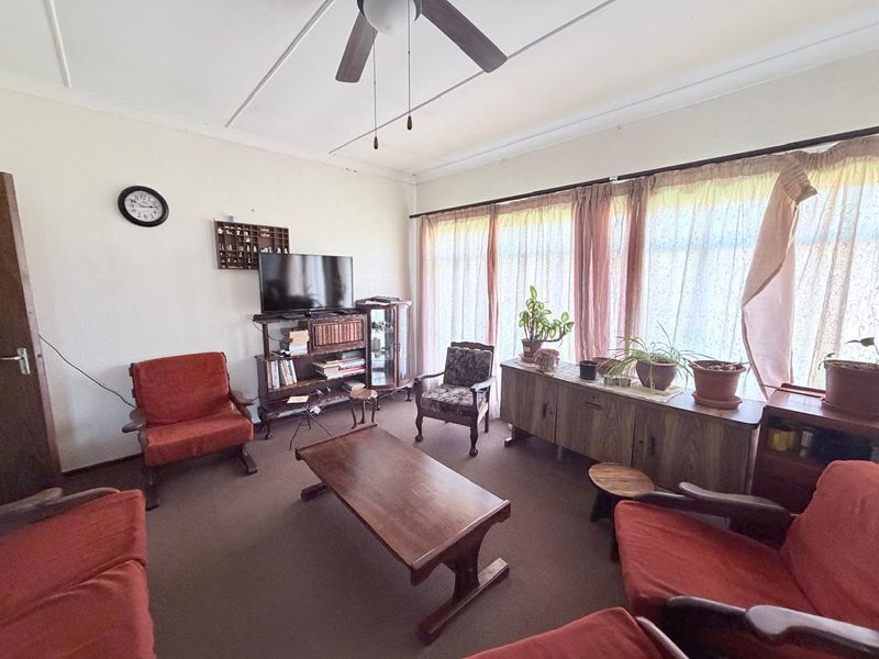 A living room featuring a ceiling fan and large windows that provide natural light.