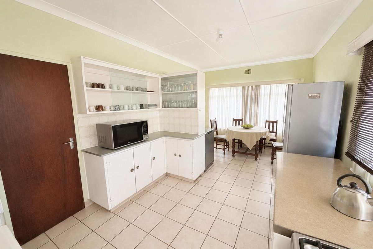 A functional kitchen featuring white built-in cabinetry, tiled flooring, and ample counter space, with an adjacent dining area.