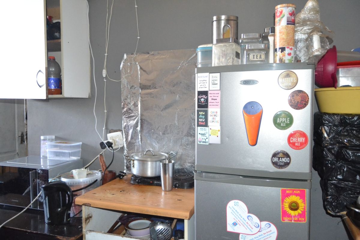 A small kitchen area featuring wall-mounted cabinetry and basic electrical infrastructure, currently showing signs of wear and requiring maintenance or renovation.