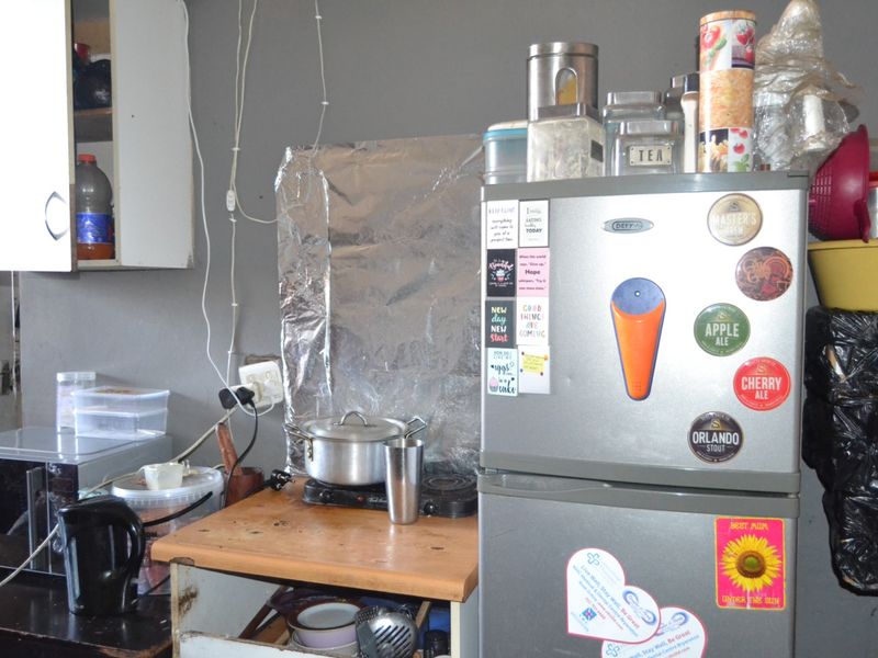 A small kitchen area featuring wall-mounted cabinetry and basic electrical infrastructure, currently showing signs of wear and requiring maintenance or renovation.