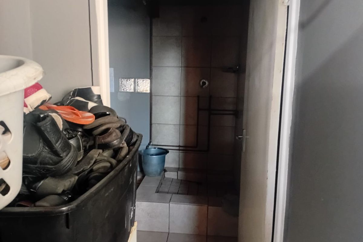 A small bathroom featuring a tiled shower enclosure with visible plumbing pipes and tiled flooring.