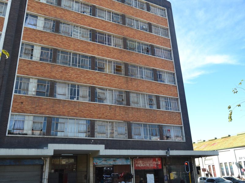 Exterior view of a multi-story apartment building featuring a brick facade and ground-level commercial storefronts.