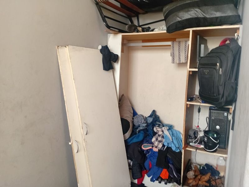 A bedroom featuring a built-in wardrobe unit that requires repair and maintenance to restore its functionality and appearance.