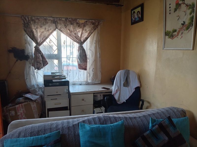 A small home office space featuring a built-in desk and security bars on the window, requiring cosmetic updates to the wall finishes.