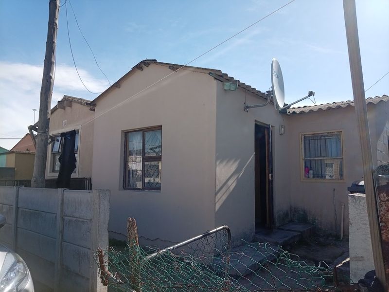 Front exterior view of a single-story house featuring a tiled roof, security bars on windows, and a perimeter fence.