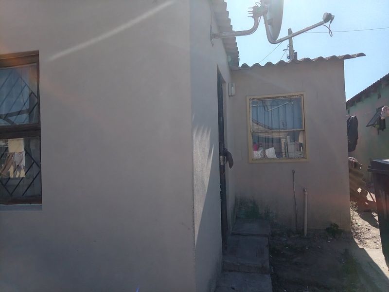 Rear exterior view of the property showing basic masonry construction, security bars on windows, and a satellite dish installation.