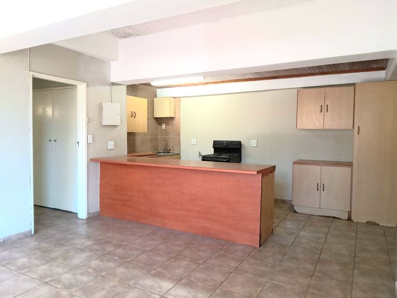 Open plan kitchen area featuring tiled flooring, built-in cabinetry, a breakfast bar, and a freestanding stove, offering a functional layout ready for modernization.