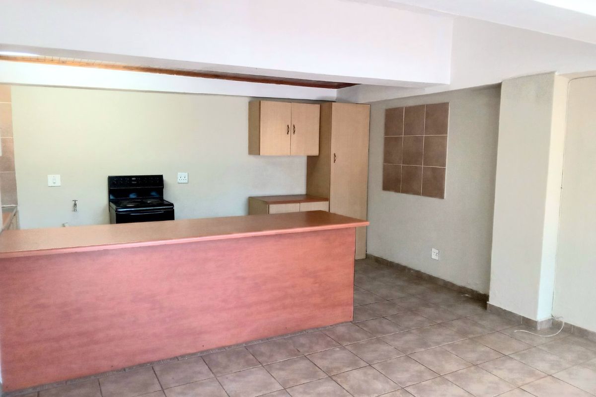 An empty kitchen area featuring tiled flooring, built-in cabinetry, a breakfast bar, and a freestanding stove.